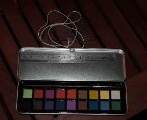 Watercolour paints tin along with spare brush, short metal ruler and a protractor.